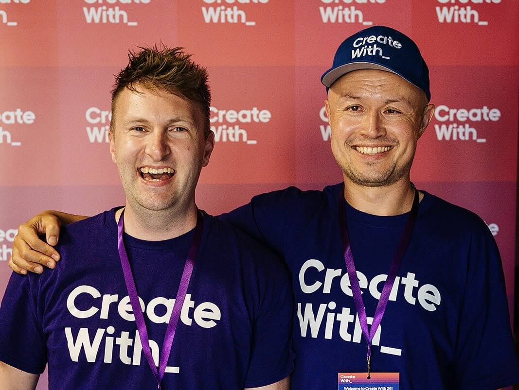 Kieran and James in Create With T-shirts, grinning in front of a Create With backdrop